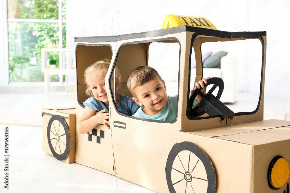 Little children playing with cardboard taxi in light room Little children playing with cardboard taxi in light room