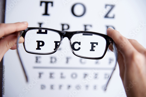 Glasses in the hands on the background of the table for vision
