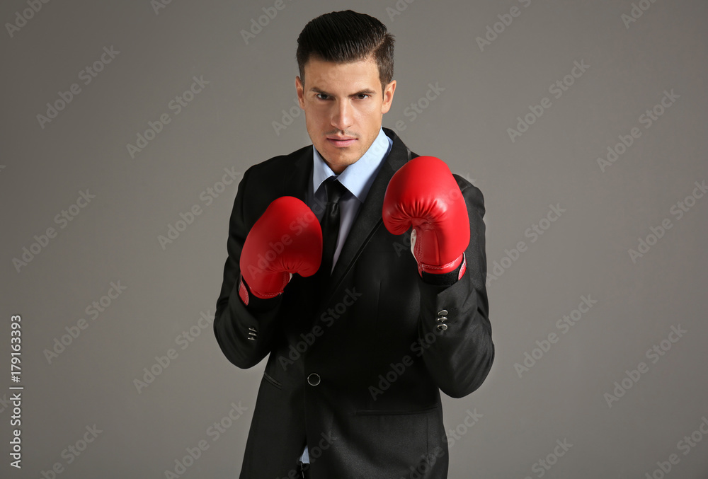 Businessman in boxing gloves on grey background Businessman in boxing gloves on grey background
