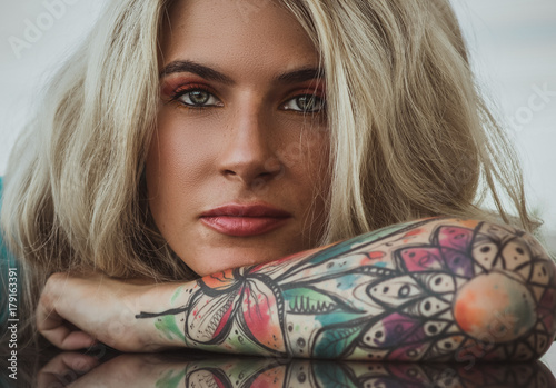 Closeup portrait of. Beautiful girl put her head in her arms with tattoos. expectation. photo