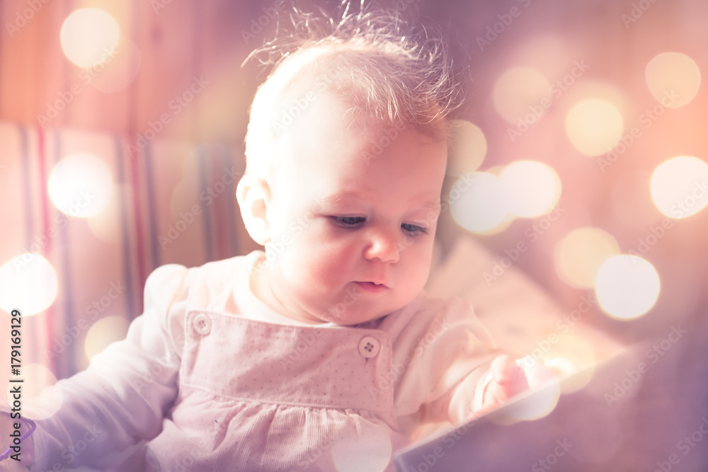 Beautiful baby looking surprise among fairy lights in pink toned colors Beautiful baby looking surprise among fairy lights in pink toned colors