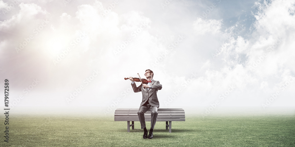 Handsome businessman in park on wooden bench play his melody Handsome businessman in park on wooden bench play his melody