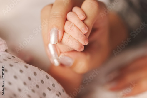 mother holds little hand of newborn baby
