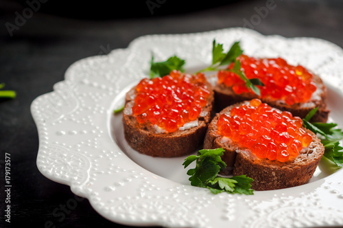 red caviar on black bread with butter. Healthy food. Fish appetizer. dark background