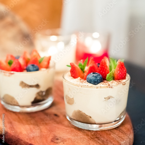 Homemade italian dessert tiramisu with strawberries, mint and blueberry in glass