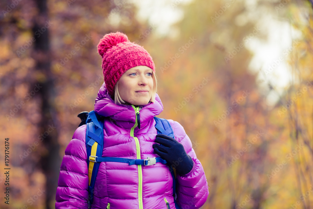 Hiking woman with backpack looking at inspirational autumn golden forest