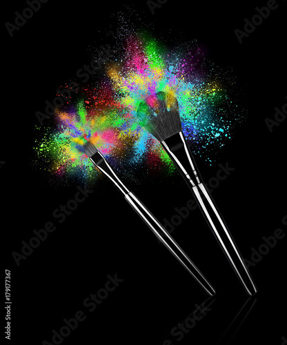 Make up brushes with explosions of colorful powder close-up on black background