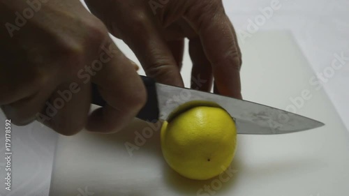 Women's hands cut lemon slice with knife into a half