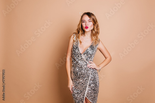 Cuadro en lienzo Elegant caucasian woman with curly hairstyle posing with kissing face expression at chrismas party