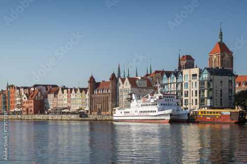 View of two boats and old buildings at the Long Bridge waterfront at the Main Town in Gdansk, Poland, on a sunny day.