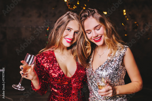 Canvas Print Indoor portrait of pleased caucasian woman in trendy sparkle attire enjoying christmas party with best friend