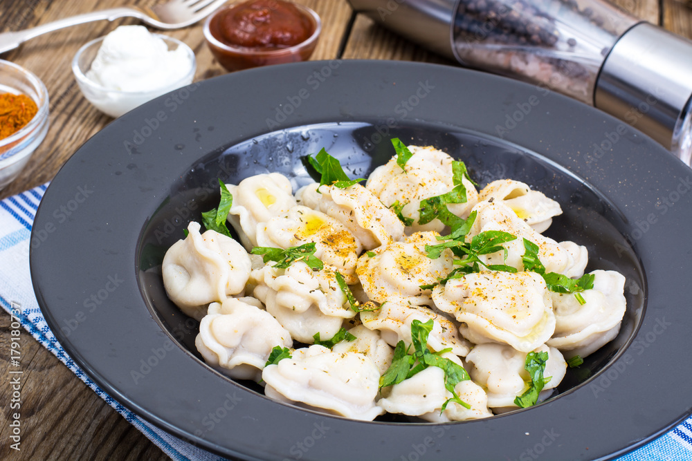 Black plate with boiled vegetarian vegetable dumplings Black plate with boiled vegetarian vegetable dumplings