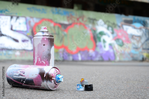 Several used spray cans with pink and white paint and caps for spraying paint...