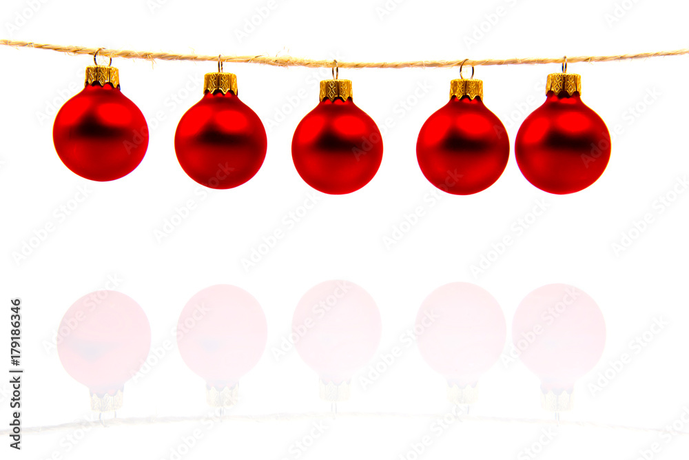 Red balls for Christmas tree hanging on a scaffold isolated on white background with reflection.