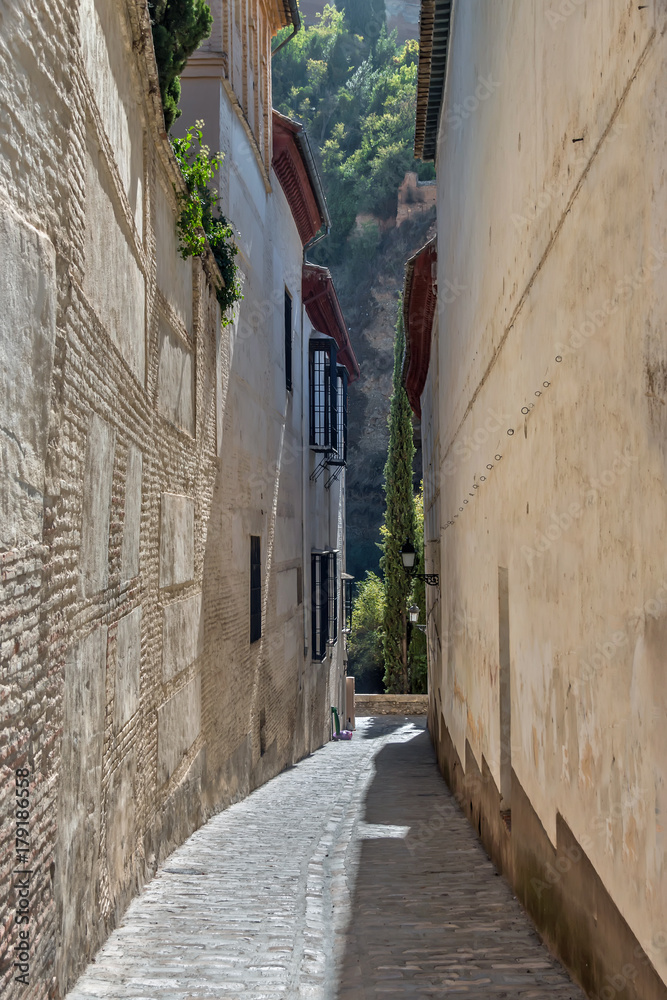 Old narrow street perspective at Albayzin district in Granada city, Spain