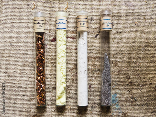 four old test tubes with different chemicals for testing on an old cloth photo