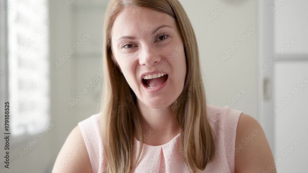 Young woman sitting at home talking via messenger app Skype. Smiling waving hand in greeting. Remote communication Young woman sitting at home talking via messenger app Skype. Smiling waving hand in greeting. Remote communication