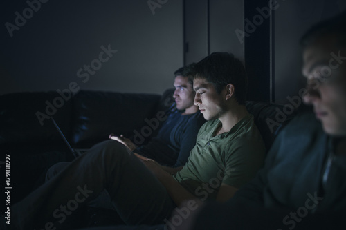 Student Friends and Rommates Watching TV together and Using Smartphones and Laptop photo