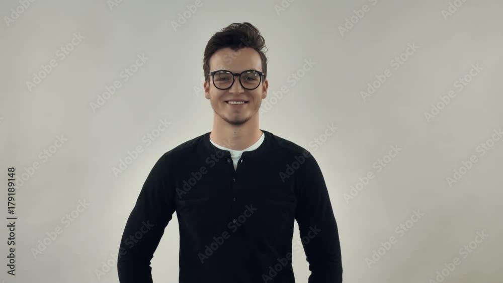 Caucasian millennial guy put on glasses. Smart cheerful man wearing casual shirt looking at camera with friendly smile.