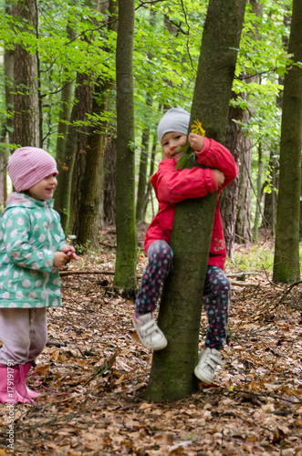 Dwie małe dziewczynki wskakują na drzewo w lesie.