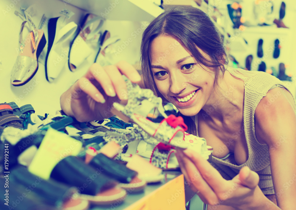 Fototapeta premium Portrait of woman looking after pair of shoes for kid