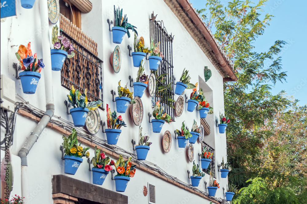 Beautiful typical andalusian facade with blue flower pots hanging on it
