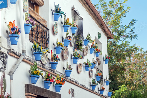 Beautiful typical andalusian facade with blue flower pots hanging on it © nobelio12