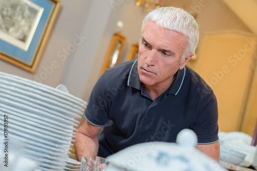 Man examining stack of crockery