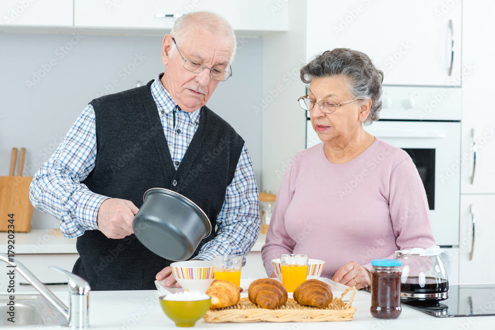 aged couple cooking and eating in the kitchen aged couple cooking and eating in the kitchen