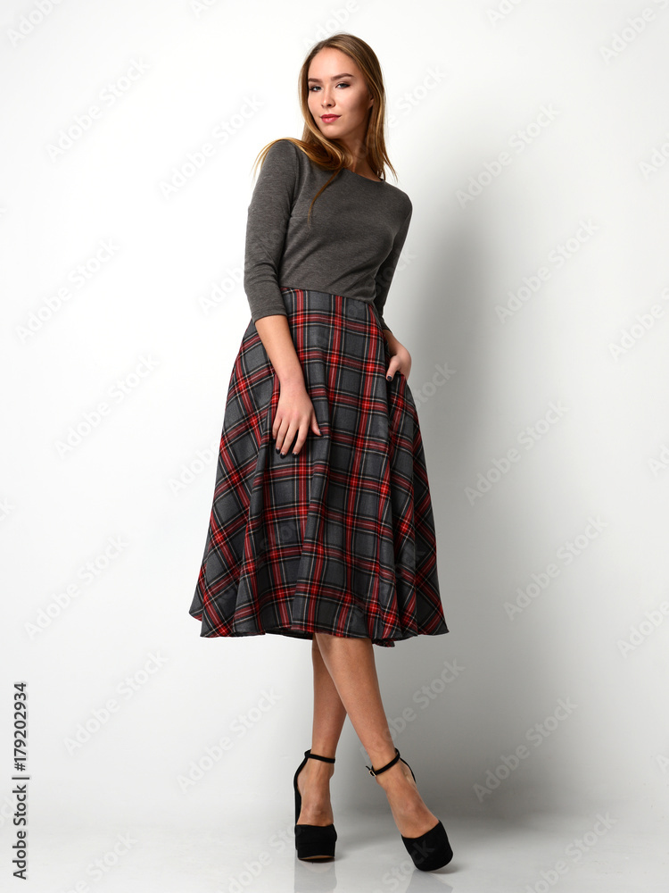 Fototapeta premium Young beautiful woman posing in new fashion plaid skirt and gray full body