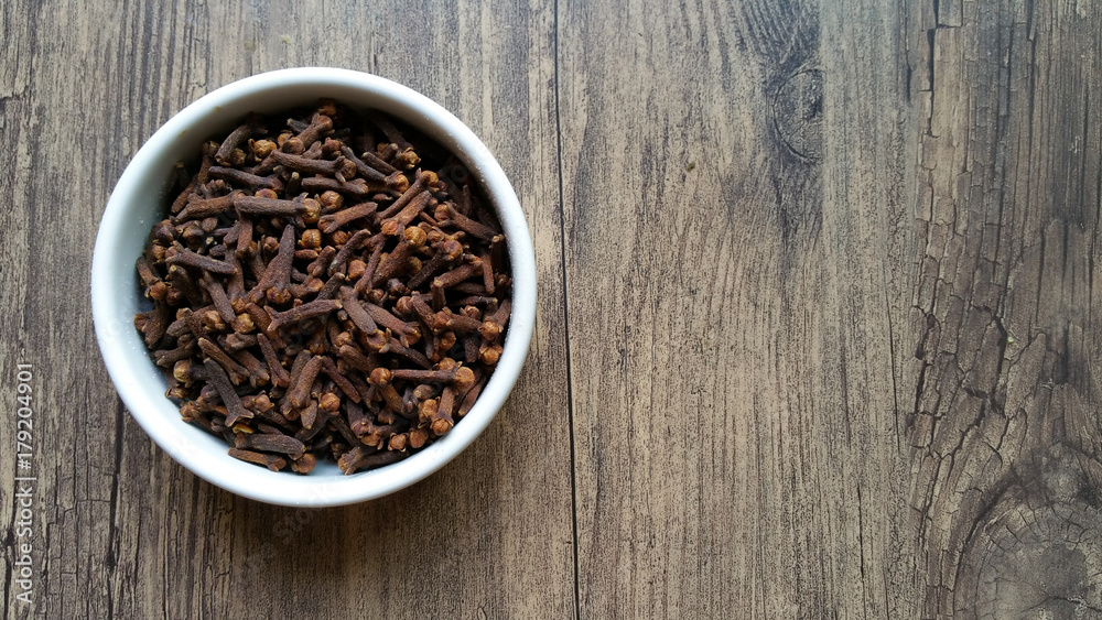 Cloves in white glass bowl on wooden background Cloves in white glass bowl on wooden background