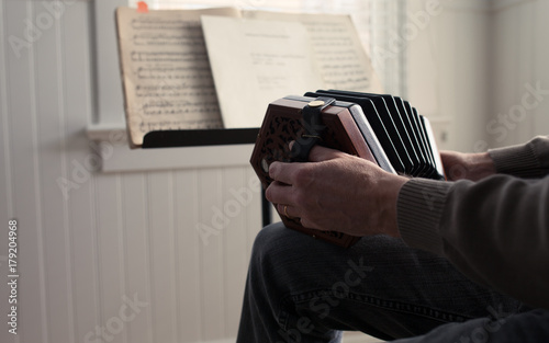 hands holding concertina in front of sheet music