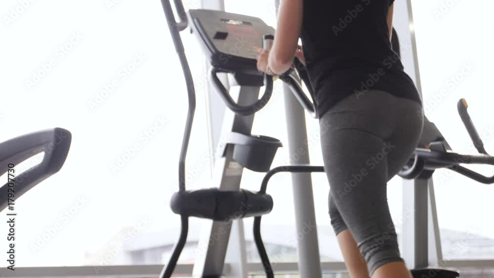 young woman at the gym exercising on the xtrainer machin