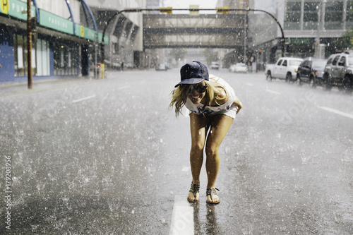 Happy young woman standing in the street in rain photo