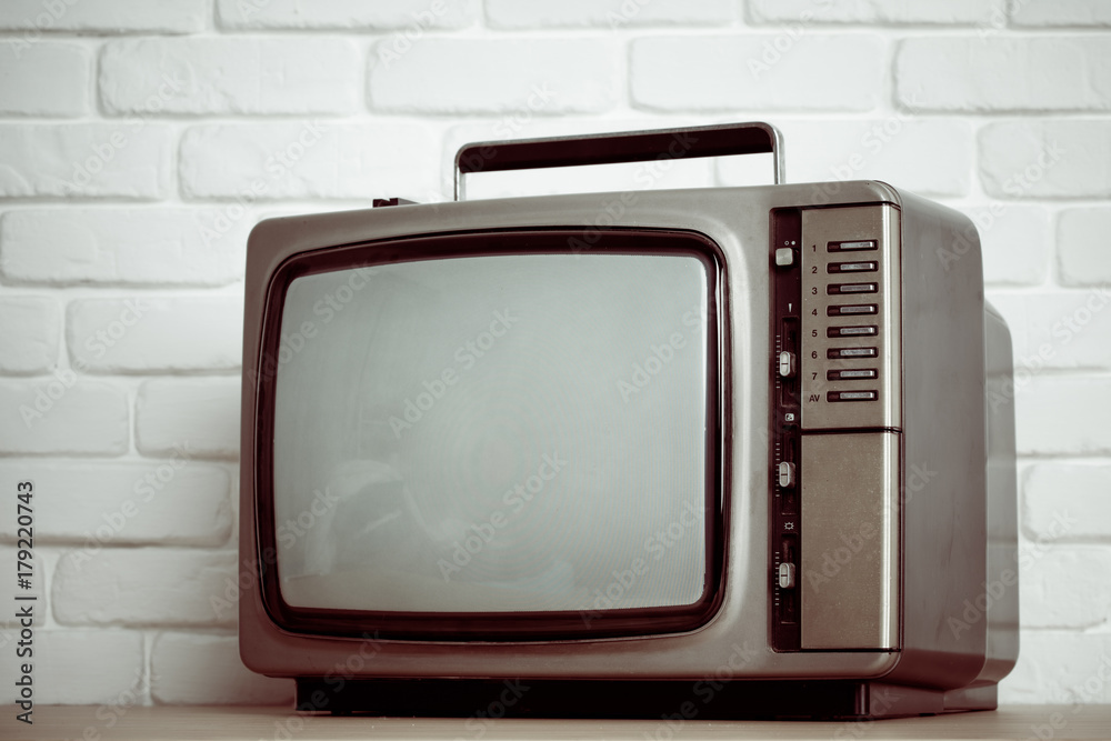 Old television on a white brick wall background.