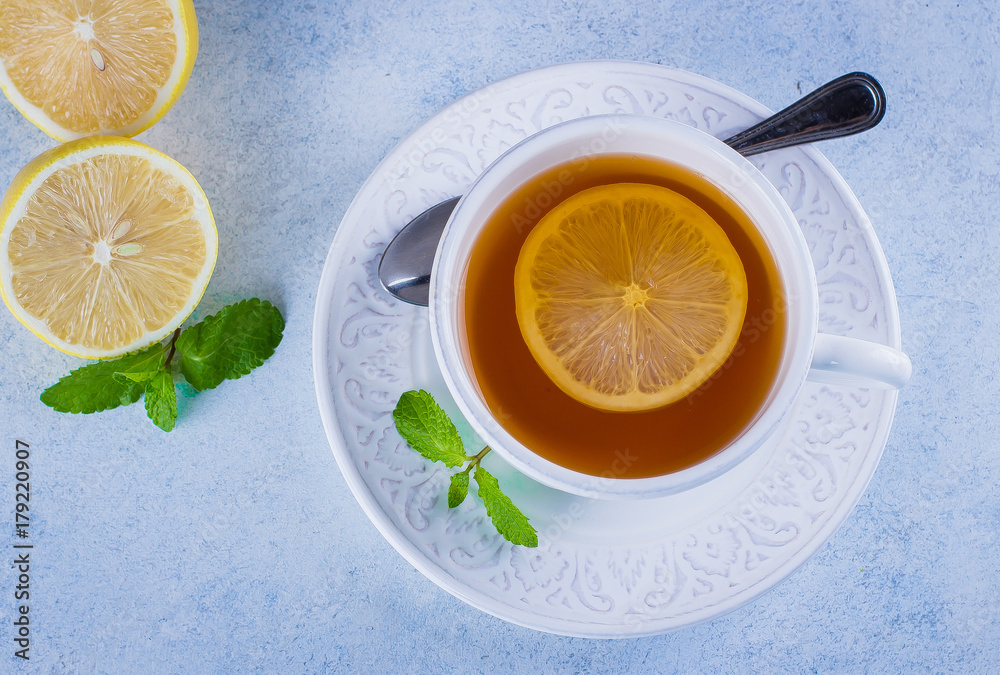 Cup of hot lemon tea with mint on blue stone table background. Healthy drink cold. Copy space. Winter drink Cup of hot lemon tea with mint on blue stone table background. Healthy drink cold. Copy space. Winter drink