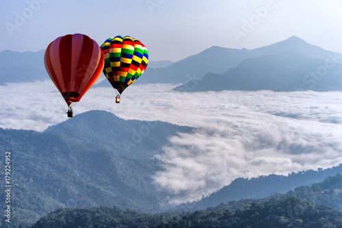 Hot air balloon with tourist is traveling into the peak of mountain and cloudscape at Doi Pha Tang in Chiangrai Provice, Thailand