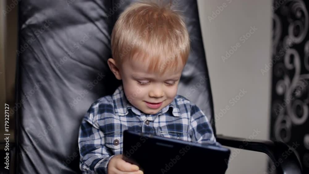 The little boy plays on a Tablet PC, close-up. Close-up of a young boy playing a game on his digital tablet. The little boy plays on a Tablet PC, close-up. Close-up of a young boy playing a game on his digital tablet.