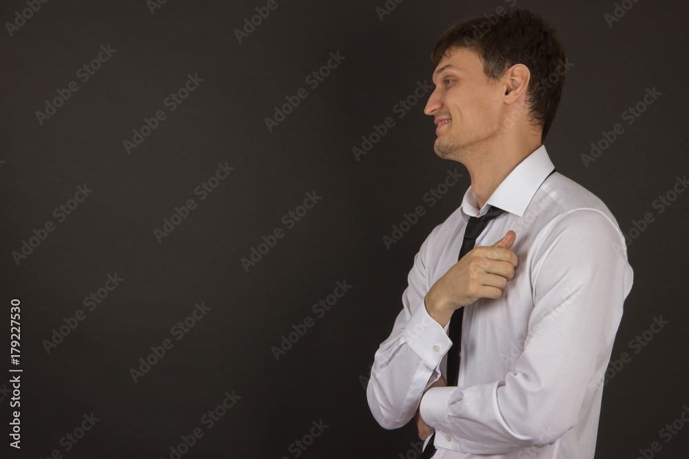 Sexy young man in a white shirt with a black tie and expensive cufflinks on the black background Sexy young man in a white shirt with a black tie and expensive cufflinks on the black background