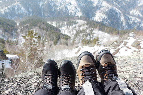 Male and female legs in trekking boots at the edge of the mountain