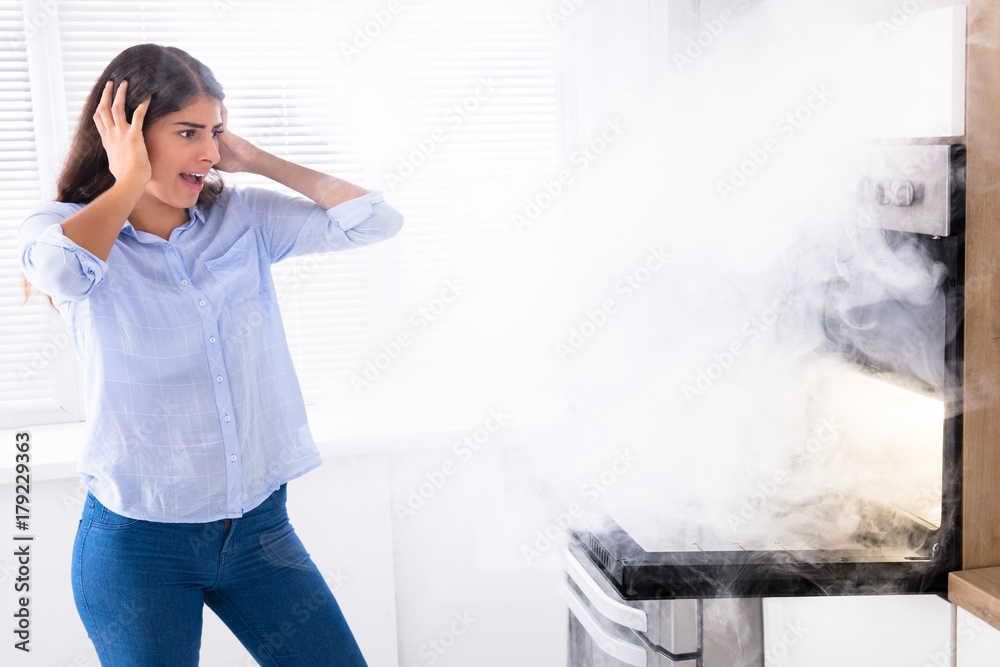 Shocked Woman Looking At Smoke Coming From Oven StockFoto Adobe Stock
