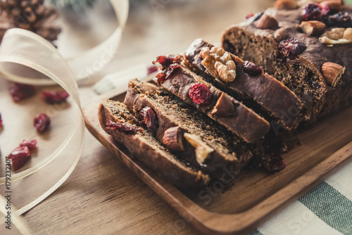 Beautiful tasty dried mixed nut Christmas fruit cake on wooden table with decorating items