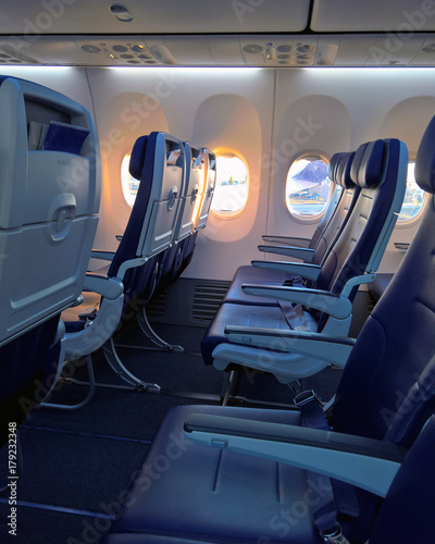 Empty row of seats on a narrow body jet airliner, sunrise