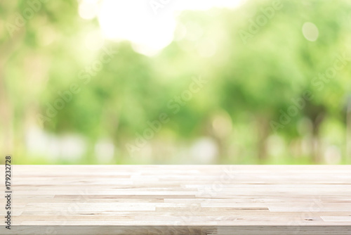Wood table top on blur green background of trees in the park