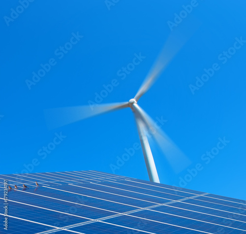 Solar panels and wind turbine against blue sky. Solar cell, solar engergy photo