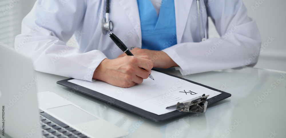 Doctor woman filling up prescription, close-up of hands. Physician at work. Medicine and healthcare concept