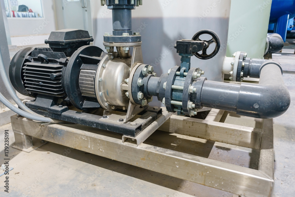 Large industrial water treatment and boiler room. Shiny steel metal pipes and blue pumps and valves. Large industrial water treatment and boiler room. Shiny steel metal pipes and blue pumps and valves.