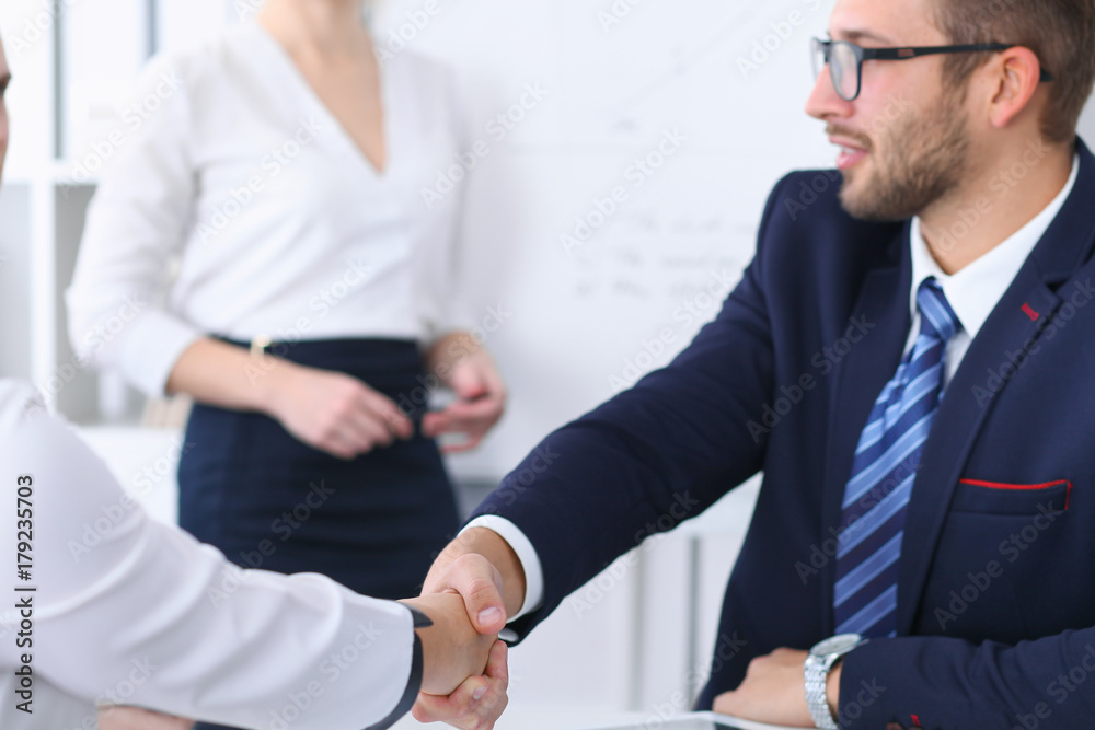 Business handshake at meeting or negotiation in the office. Partners are satisfied because signing contract or financial papers Business handshake at meeting or negotiation in the office. Partners are satisfied because signing contract or financial papers