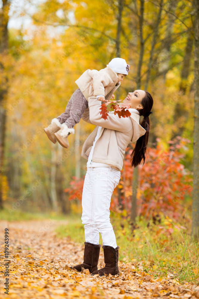 Fototapeta premium Little girl and her mother playing in the autumn park