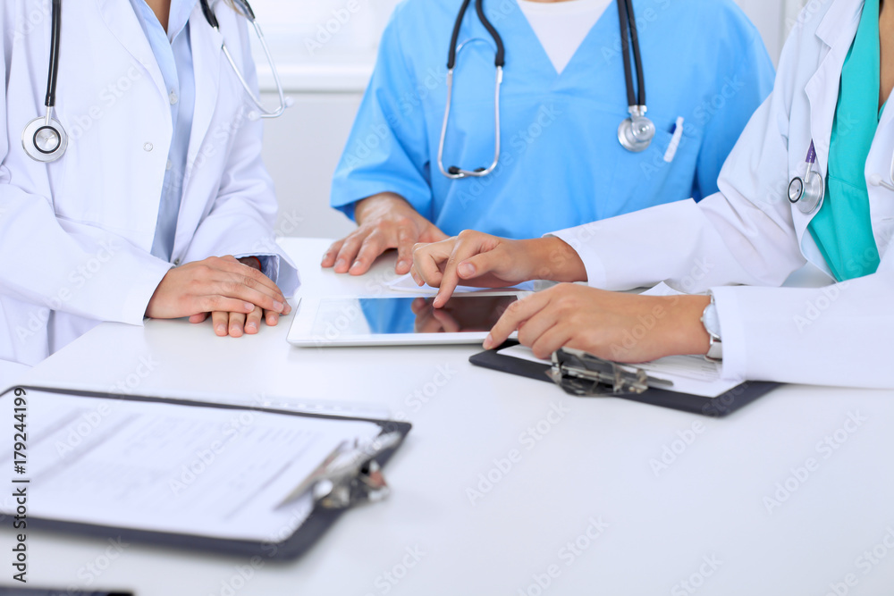 Group of doctors at medical meeting. Close up of physician using touch pad or tablet computer